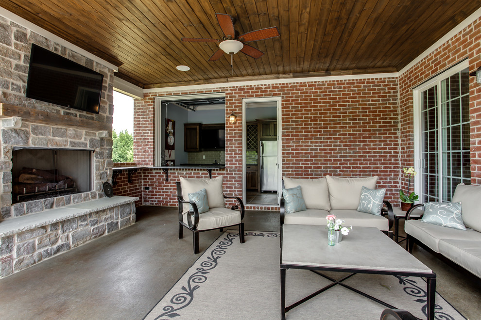 This is an example of a traditional patio in Nashville with a fire feature, concrete slabs and a roof extension.