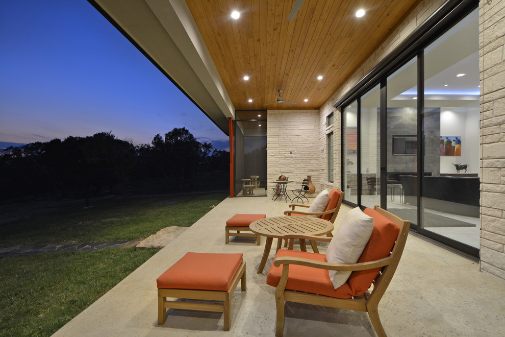 Idées déco pour une terrasse arrière moderne de taille moyenne avec une extension de toiture et une dalle de béton.