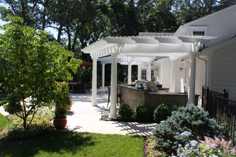 Inspiration for a mid-sized transitional backyard stone patio kitchen remodel in New York with a pergola