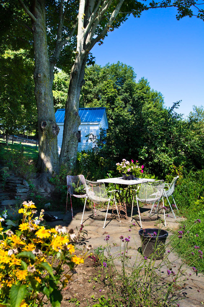 Imagen de patio de estilo de casa de campo en patio trasero con adoquines de piedra natural