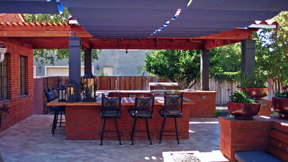Imagen de patio tradicional con adoquines de ladrillo y cocina exterior