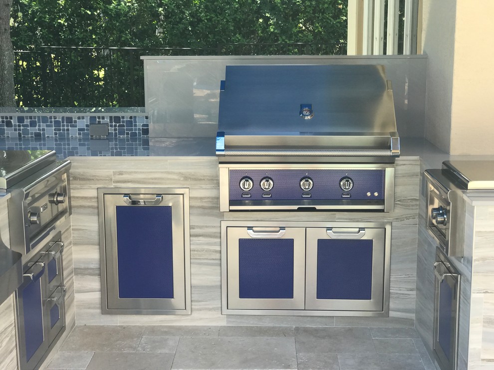 Inspiration for a world-inspired back patio in Miami with an outdoor kitchen, natural stone paving and an awning.