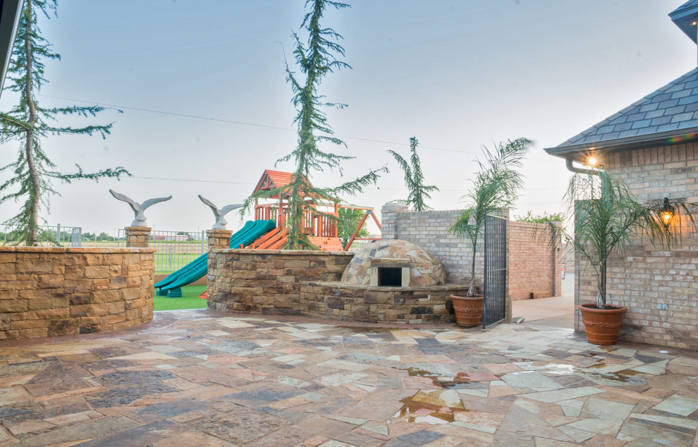 Patio kitchen - huge traditional backyard stone patio kitchen idea in Oklahoma City with a roof extension