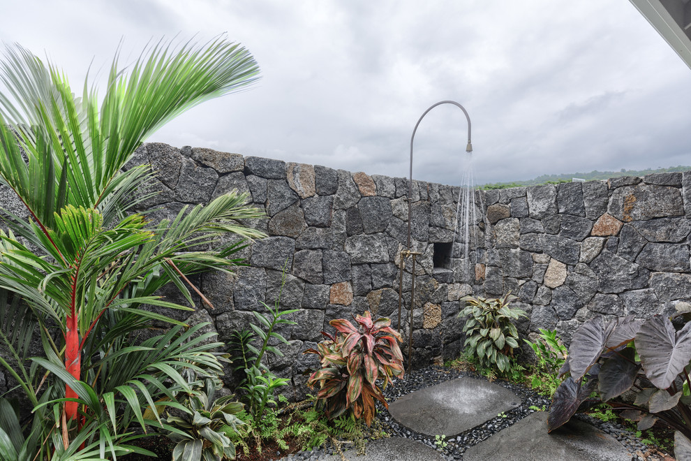 Unbedeckter Patio neben dem Haus mit Gartendusche und Natursteinplatten in Hawaii