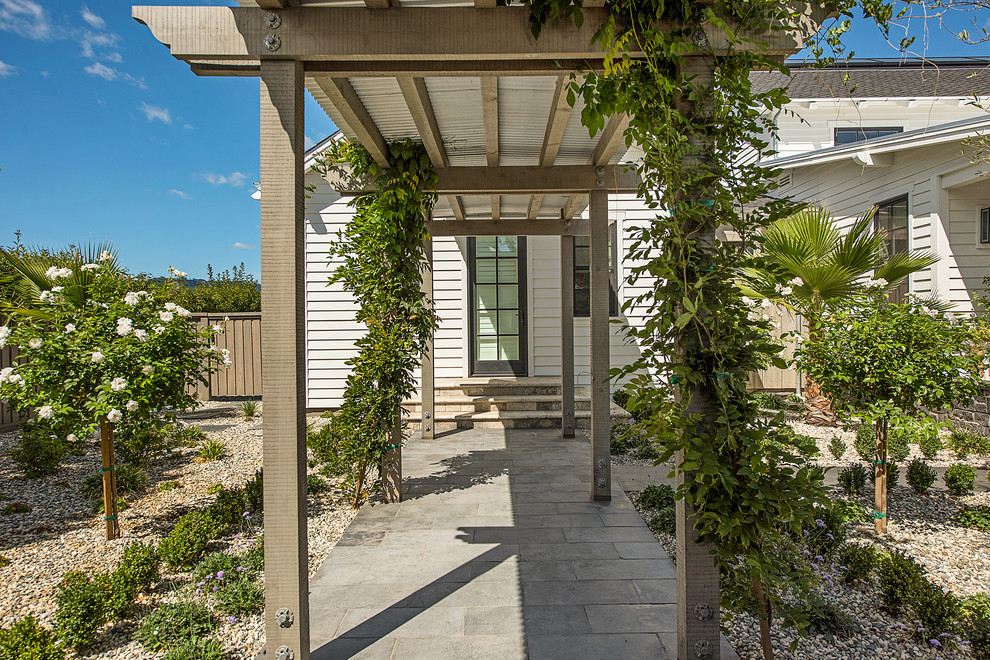 Esempio di un grande patio o portico country davanti casa con un giardino in vaso, pedane e un tetto a sbalzo