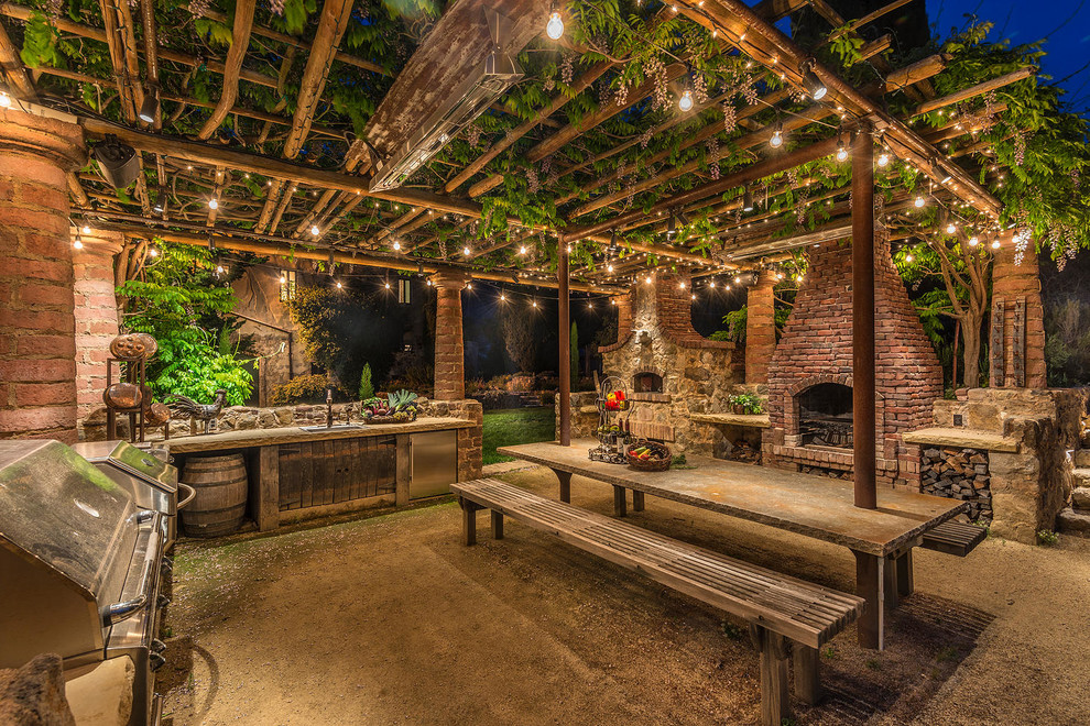 This is an example of a medium sized rustic back patio in San Francisco with an outdoor kitchen, gravel and a pergola.