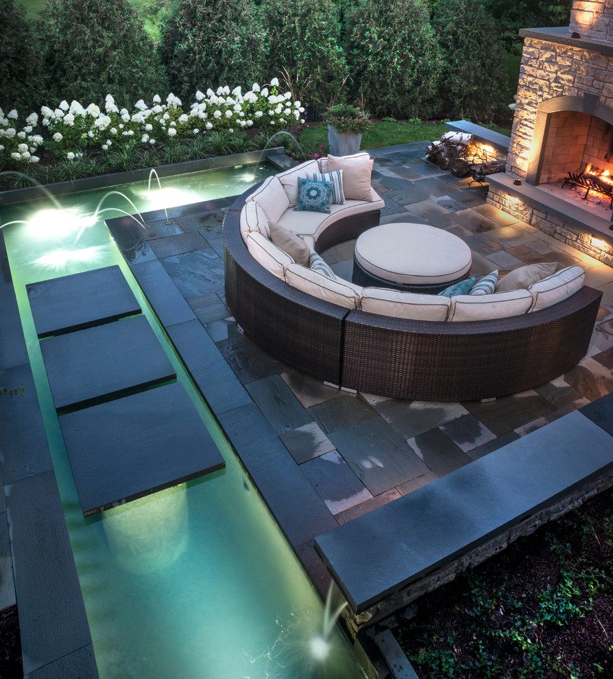 Foto de patio moderno de tamaño medio en patio trasero con fuente y adoquines de piedra natural
