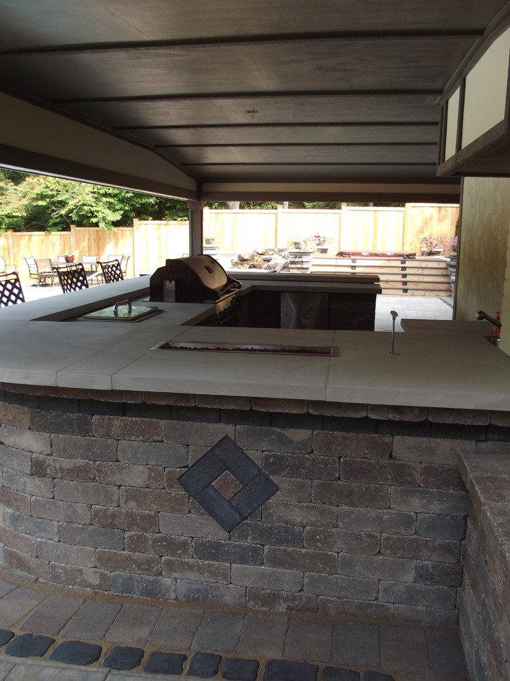 Стильный дизайн: огромный двор на заднем дворе с летней кухней, покрытием из каменной брусчатки и навесом - последний тренд