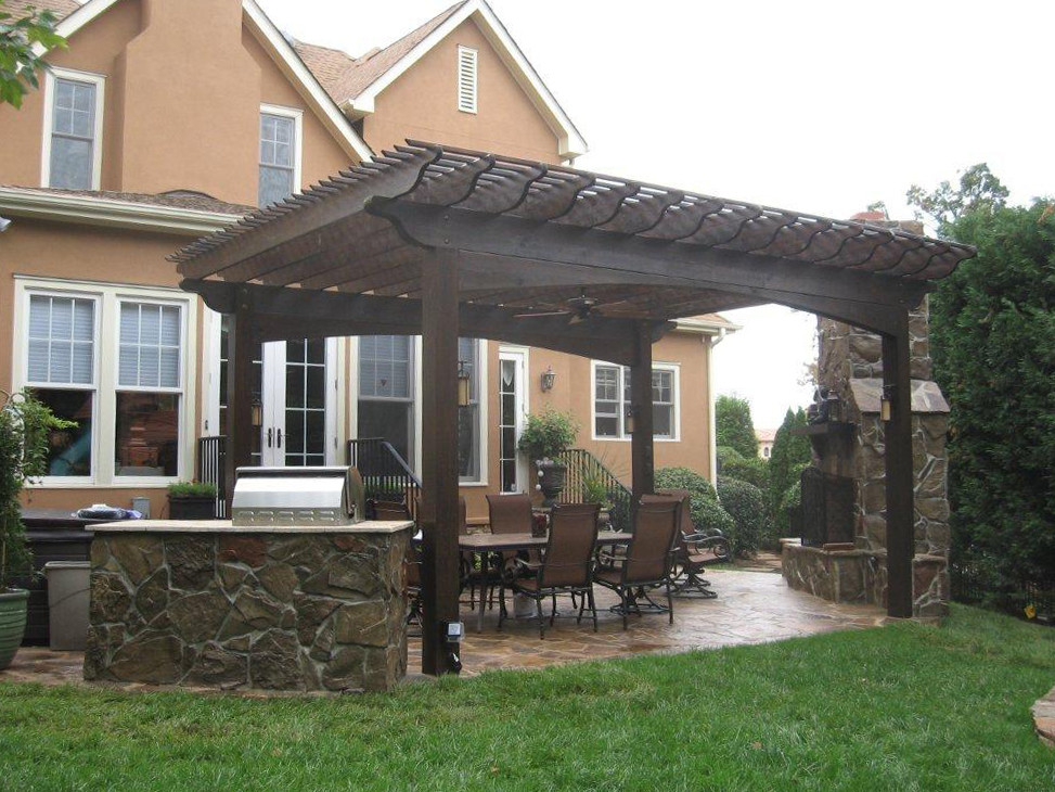 Esempio di un grande patio o portico eclettico dietro casa con un caminetto, pavimentazioni in pietra naturale e una pergola
