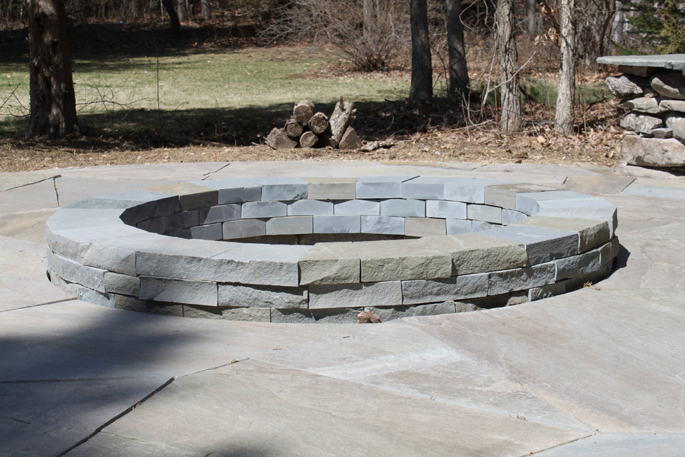 Example of a mid-sized mountain style backyard stone patio design in Detroit with a fire pit and no cover