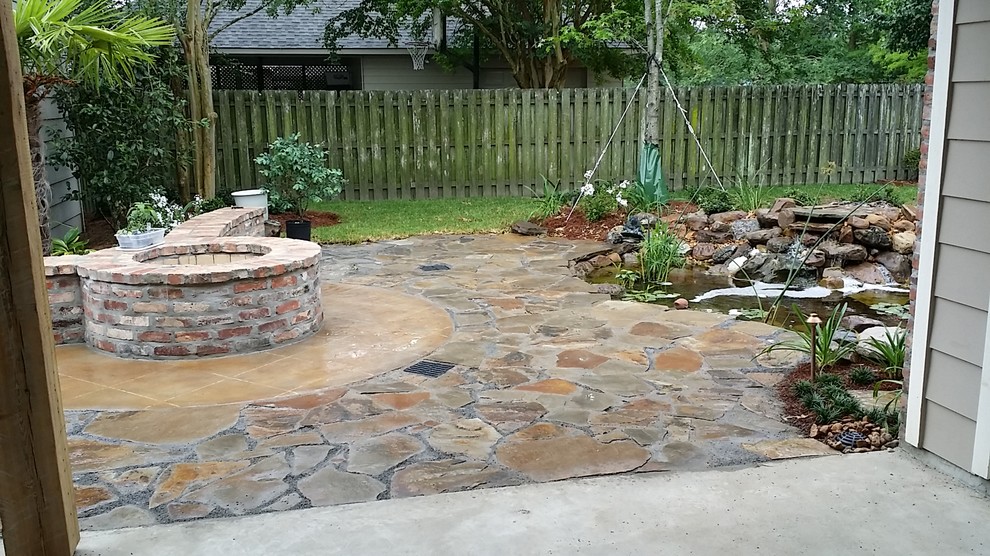 Inspiration for a medium sized eclectic back patio in New Orleans with a water feature, natural stone paving and no cover.