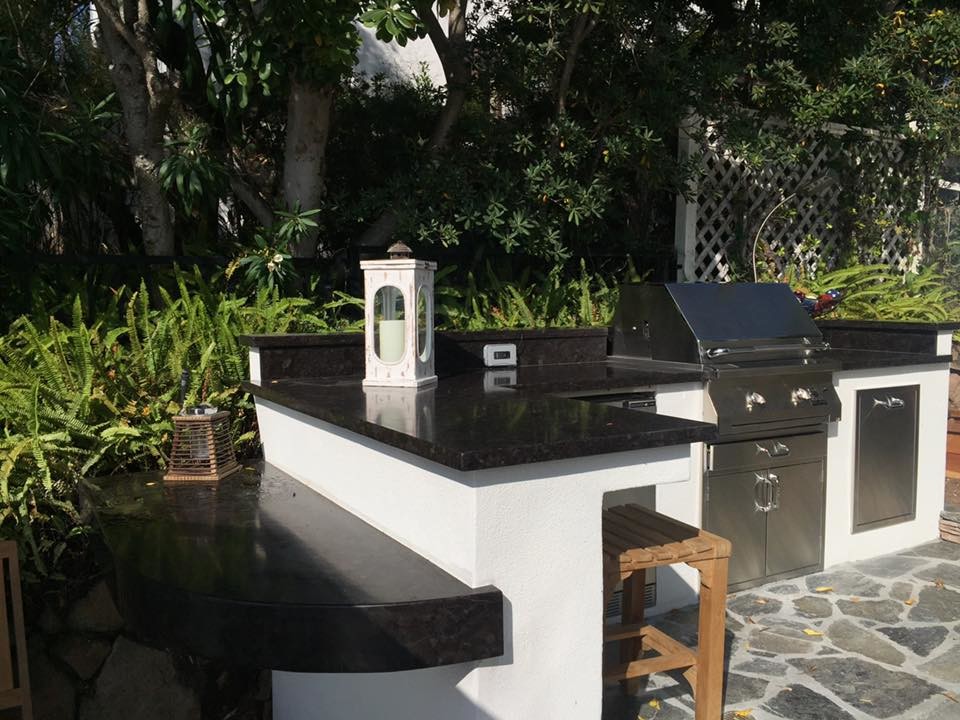Photo of a large traditional back patio in San Diego with an outdoor kitchen, natural stone paving and no cover.