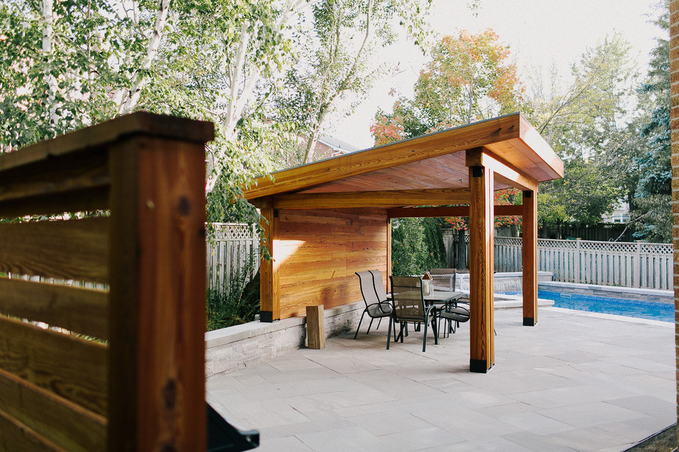 Medium sized modern back patio in Toronto with natural stone paving, a gazebo and a water feature.