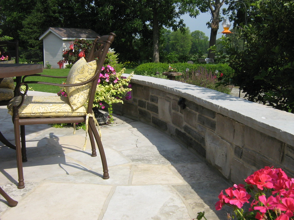 Idee per un grande patio o portico chic dietro casa con pavimentazioni in pietra naturale