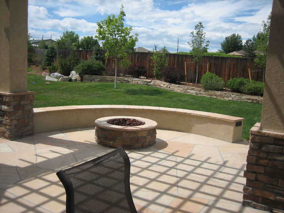 This is an example of a medium sized classic back patio in Denver with natural stone paving, a pergola and a fire feature.