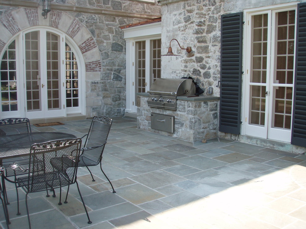 Cette image montre une terrasse arrière traditionnelle avec des pavés en pierre naturelle et une cuisine d'été.