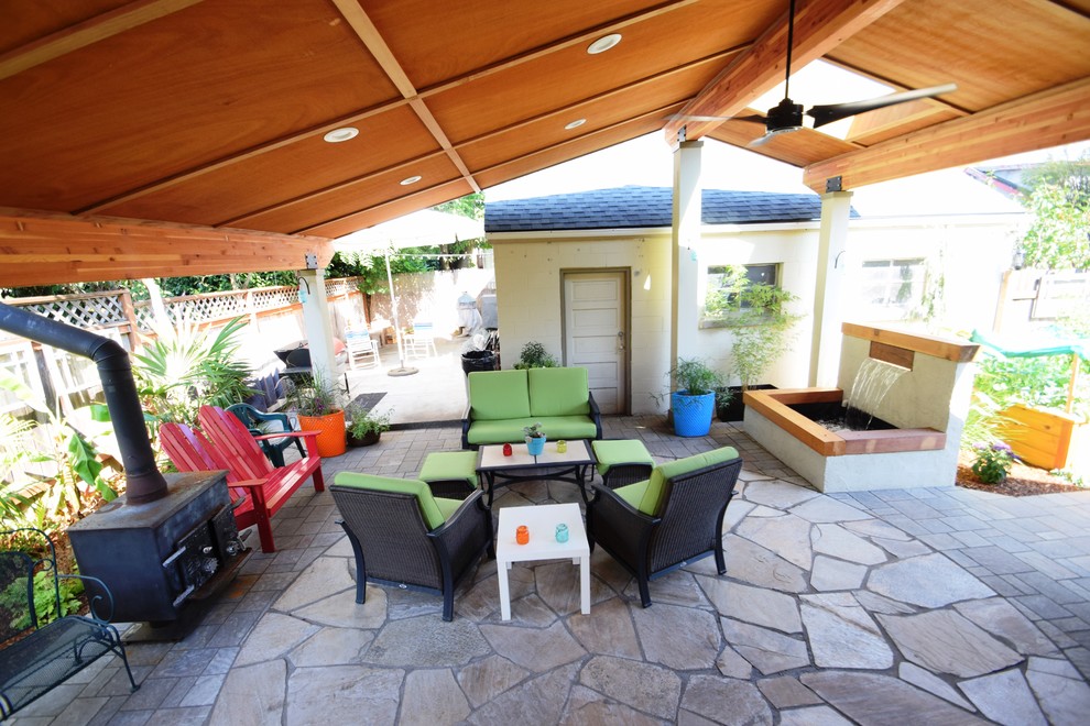 Inspiration pour une grande terrasse arrière traditionnelle avec un foyer extérieur, des pavés en béton et une extension de toiture.