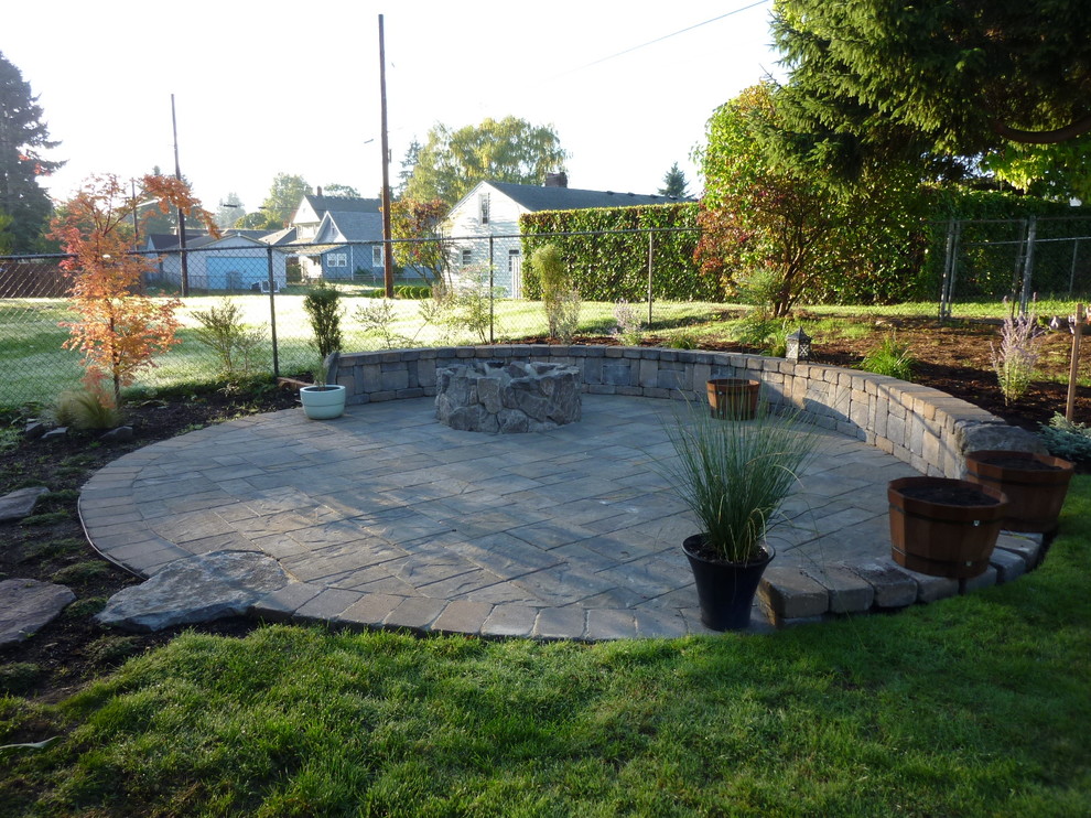 This is an example of a medium sized traditional back patio in Portland with a fire feature and concrete paving.