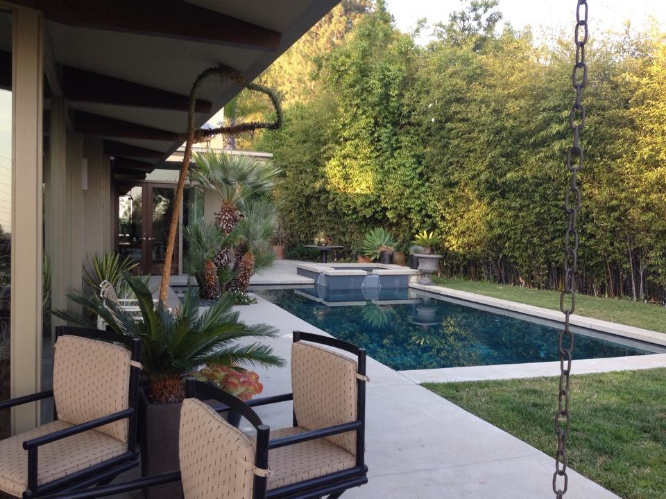 Photo of a large classic back patio in Los Angeles with a water feature, concrete paving and a roof extension.
