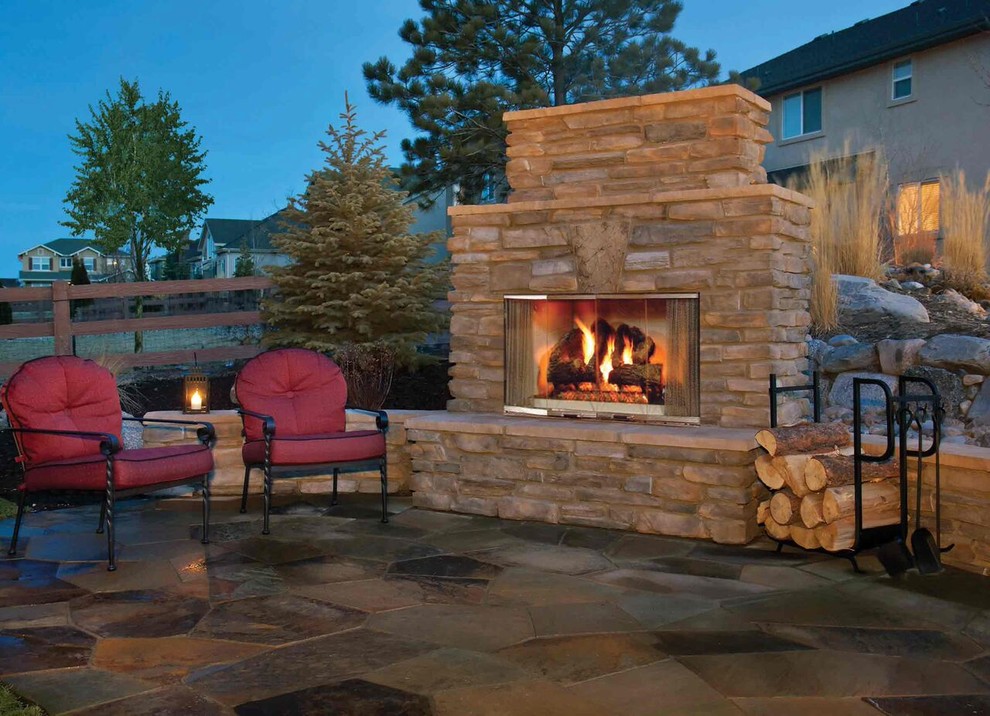 Photo of a large traditional back patio in Calgary with a fire feature, no cover and natural stone paving.