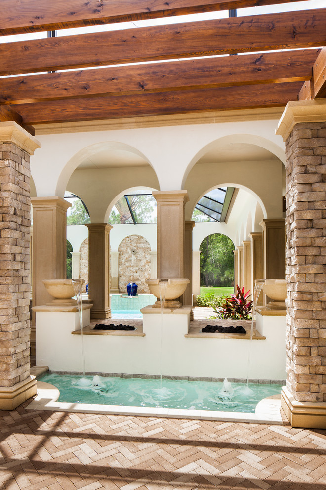 Inspiration pour une terrasse arrière méditerranéenne de taille moyenne avec un point d'eau, des pavés en pierre naturelle et une pergola.