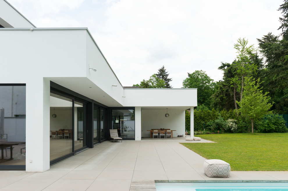 Photo of a medium sized modern back patio in Dusseldorf with a roof extension.