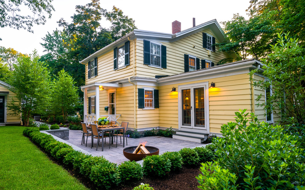 Aménagement d'une terrasse latérale classique de taille moyenne avec un foyer extérieur, des pavés en béton et aucune couverture.