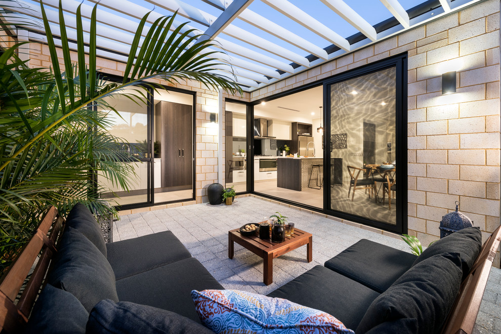 Diseño de patio contemporáneo con adoquines de hormigón y pérgola