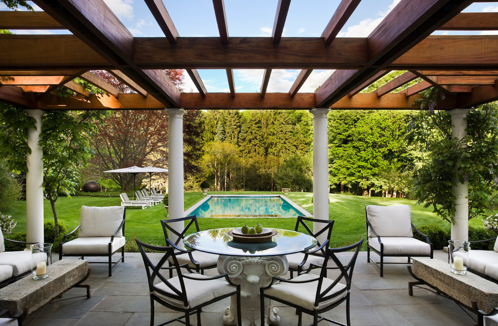 Design ideas for a large traditional back patio in New York with a pergola.