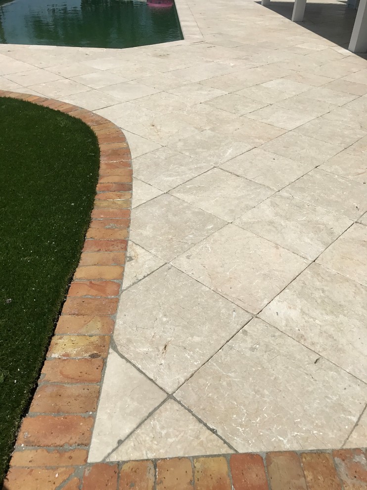 Klassischer Patio hinter dem Haus mit Natursteinplatten und Markisen in Miami