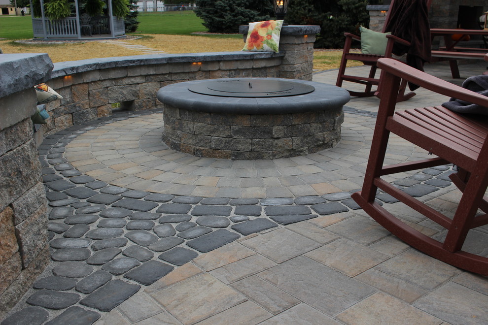 This is an example of a large rustic back patio in Philadelphia with a fire feature and concrete paving.