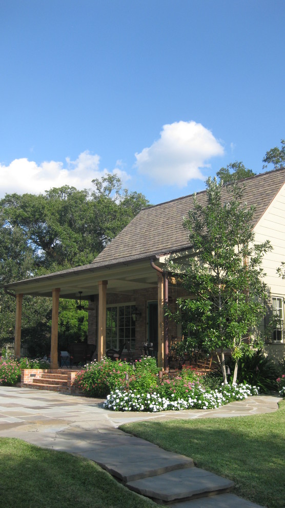 Klassisk inredning av en mellanstor uteplats på baksidan av huset, med naturstensplattor och takförlängning