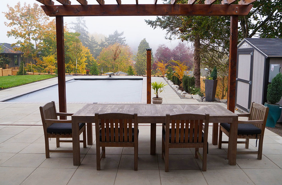 Foto di un grande patio o portico minimalista dietro casa con lastre di cemento e una pergola