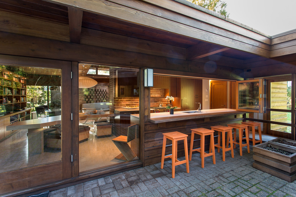 Идея дизайна: двор среднего размера на заднем дворе в стиле ретро с мощением клинкерной брусчаткой и навесом