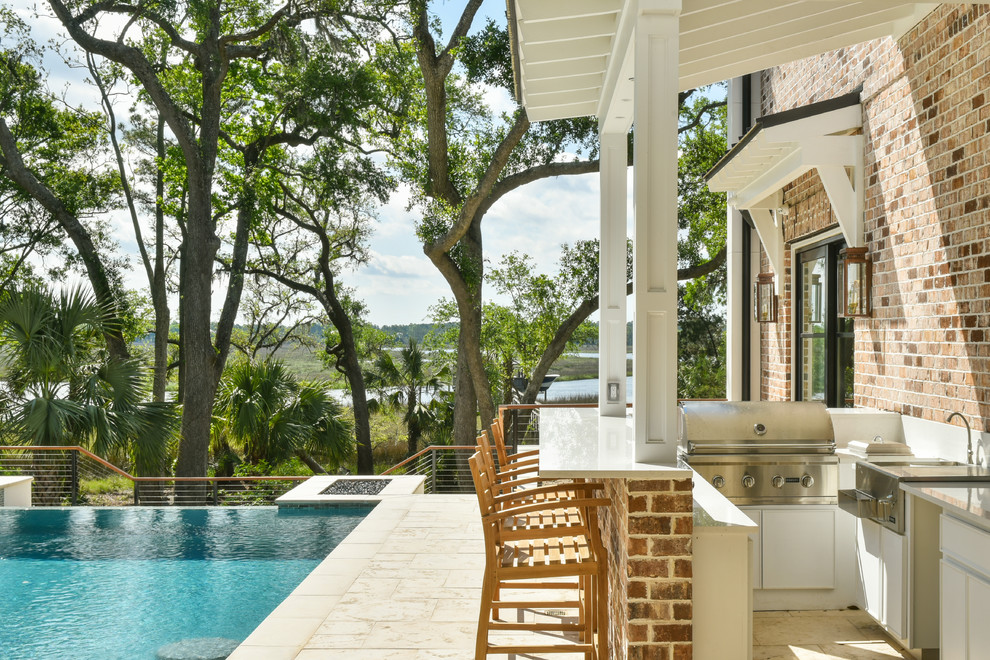 Réalisation d'une grande terrasse tradition avec une cuisine d'été, une cour, des pavés en pierre naturelle et un auvent.