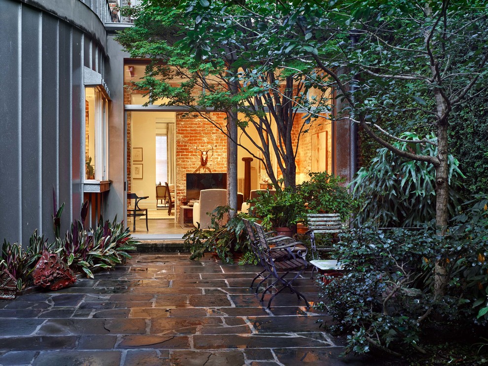 Example of a large transitional courtyard stone patio design in New Orleans with no cover