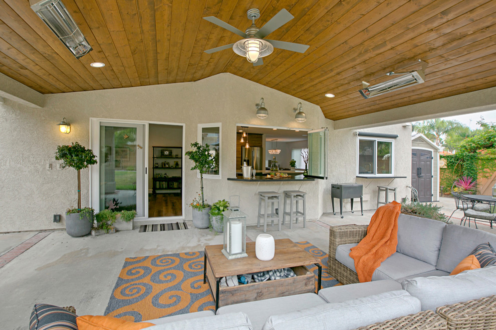 Large classic back patio in San Diego with concrete slabs and a roof extension.
