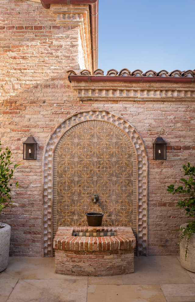 Photo of a mediterranean patio in Orange County with a water feature and no cover.