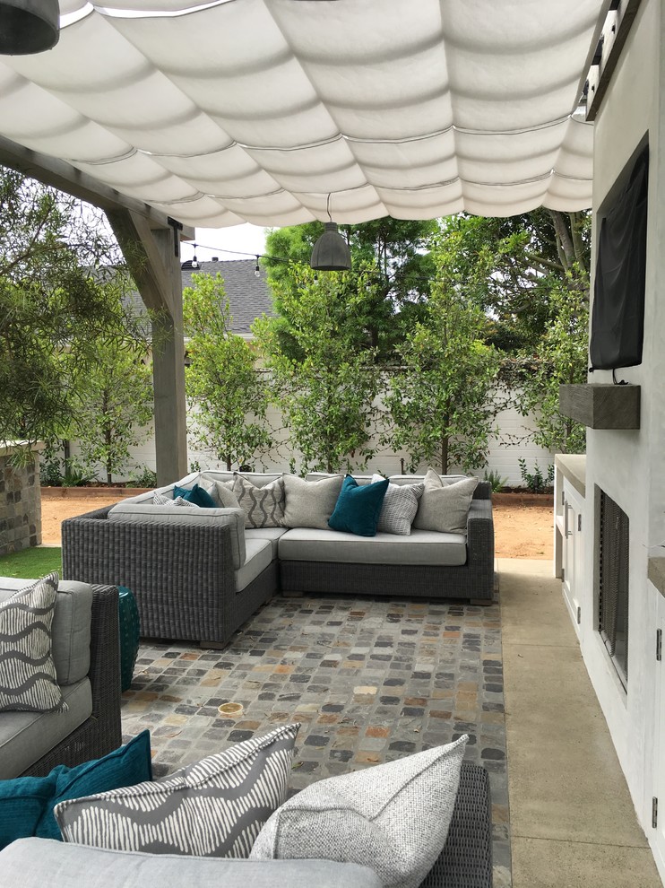 Example of a mid-sized beach style backyard stone patio design in Orange County with an awning