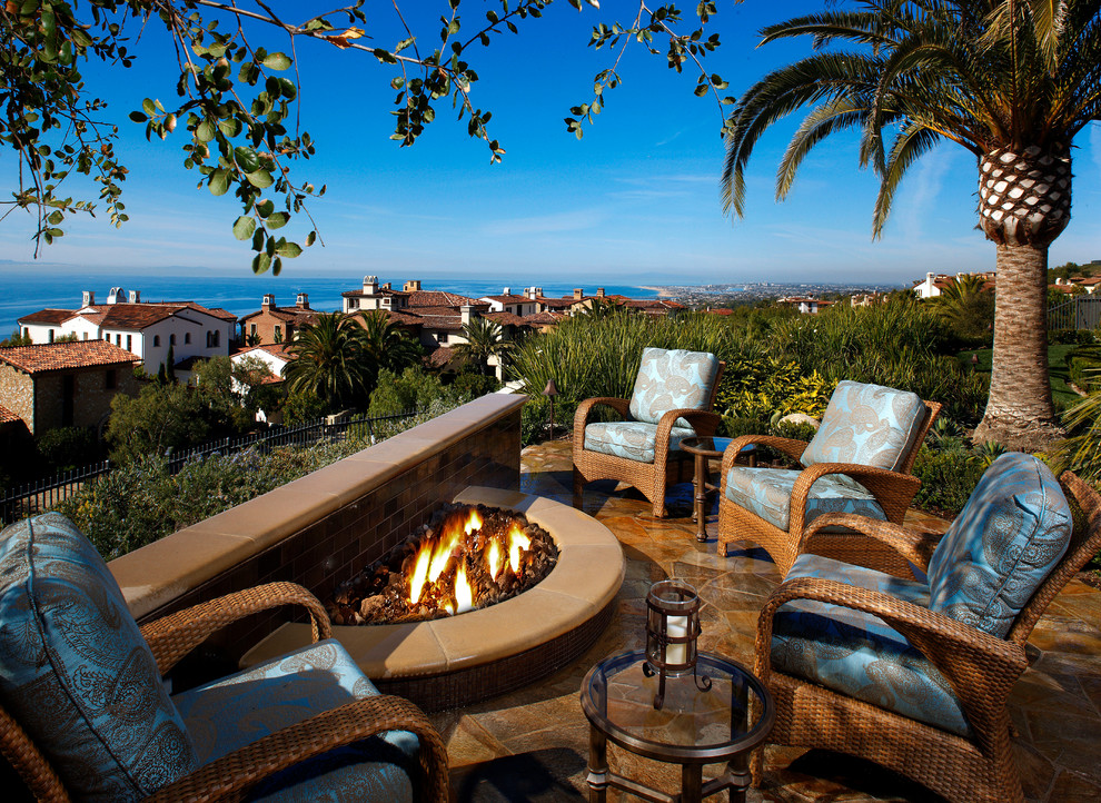 Example of a tuscan backyard patio design in Orange County with a fire pit