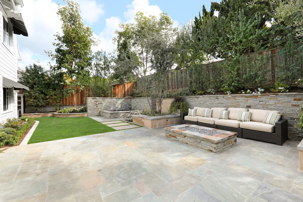 Imagen de patio clásico renovado de tamaño medio en patio trasero con brasero, adoquines de piedra natural y toldo