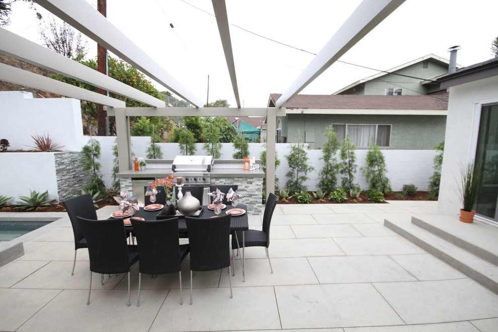 Exemple d'une terrasse arrière chic de taille moyenne avec une cuisine d'été, des pavés en béton et une pergola.