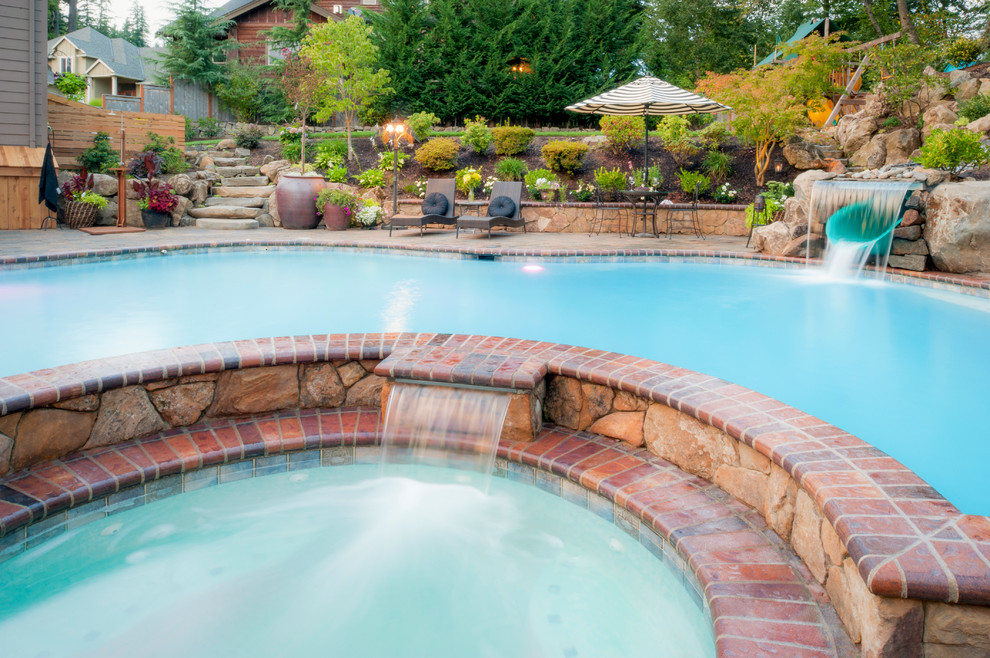 Example of a large tuscan backyard concrete paver pool design in Portland