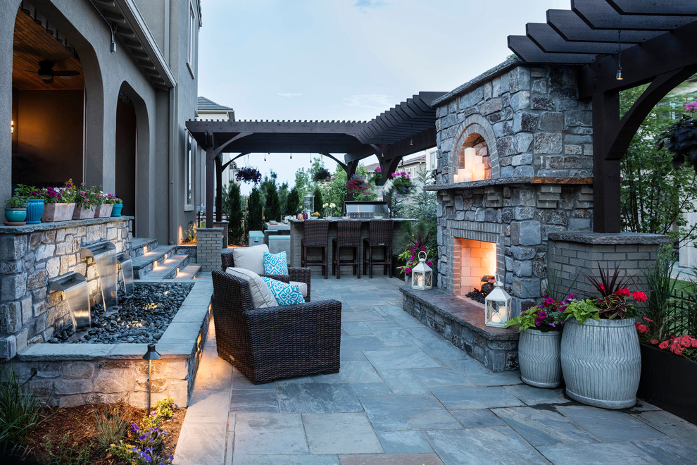 Immagine di un patio o portico minimal di medie dimensioni e dietro casa con un focolare, pavimentazioni in pietra naturale e una pergola