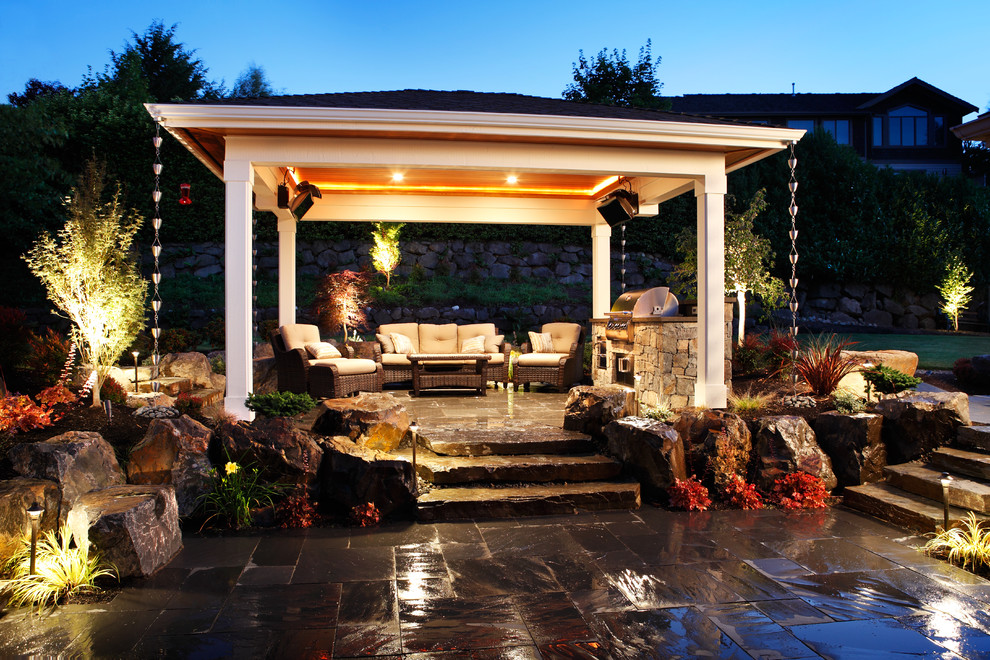 Diseño de patio en patio trasero con cocina exterior, adoquines de piedra natural y cenador