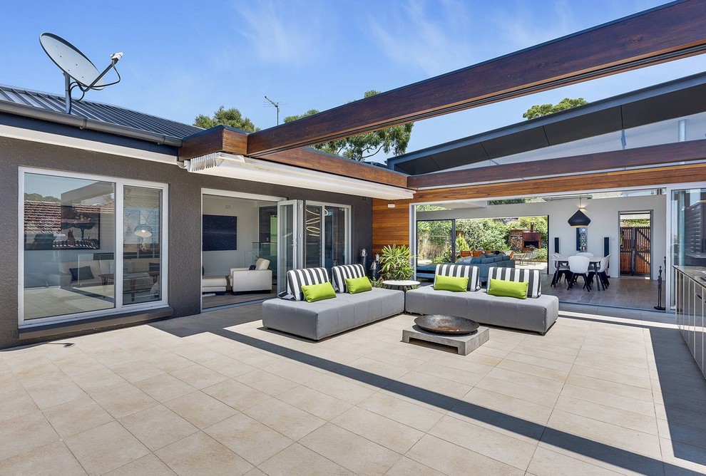 Ispirazione per un ampio patio o portico moderno in cortile con un caminetto, cemento stampato e un parasole