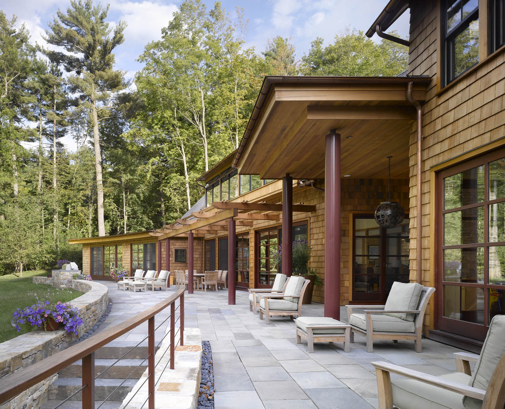 Foto di un patio o portico design con pavimentazioni in pietra naturale, un tetto a sbalzo e scale