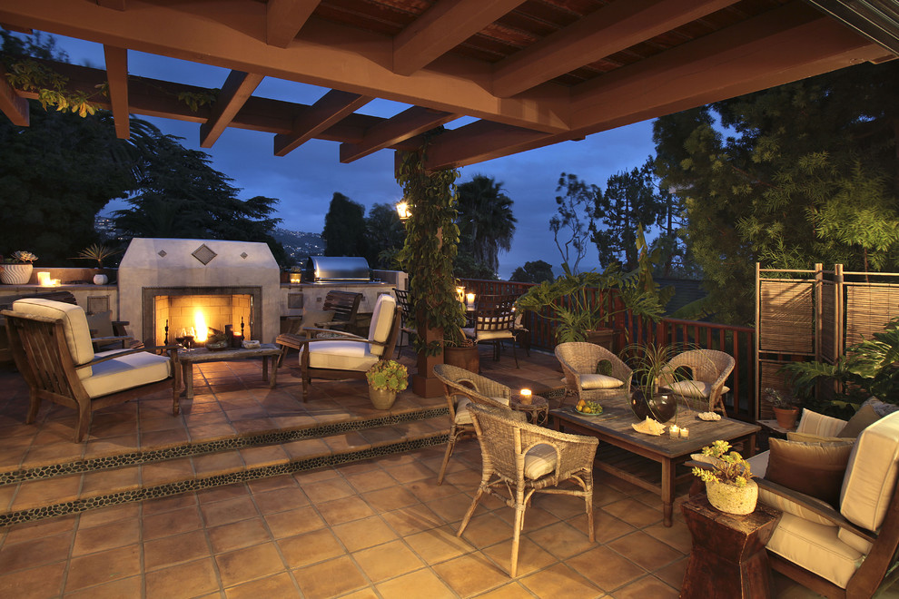 Immagine di un grande patio o portico mediterraneo dietro casa con un focolare, piastrelle e una pergola