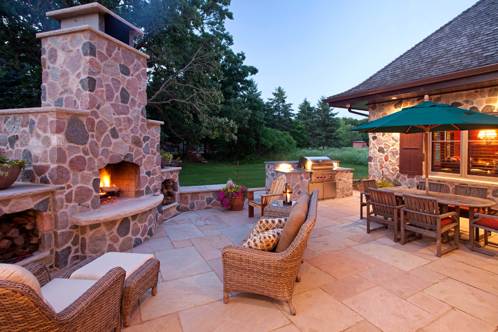 Ejemplo de patio grande sin cubierta en patio trasero con adoquines de piedra natural y chimenea