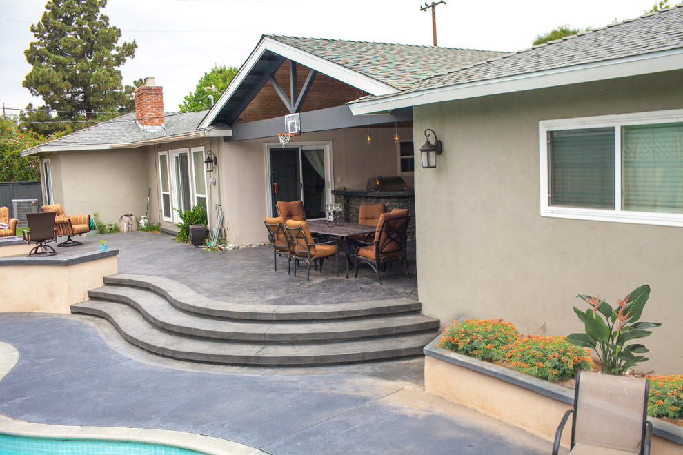 Foto di un grande patio o portico tradizionale dietro casa con cemento stampato e un tetto a sbalzo